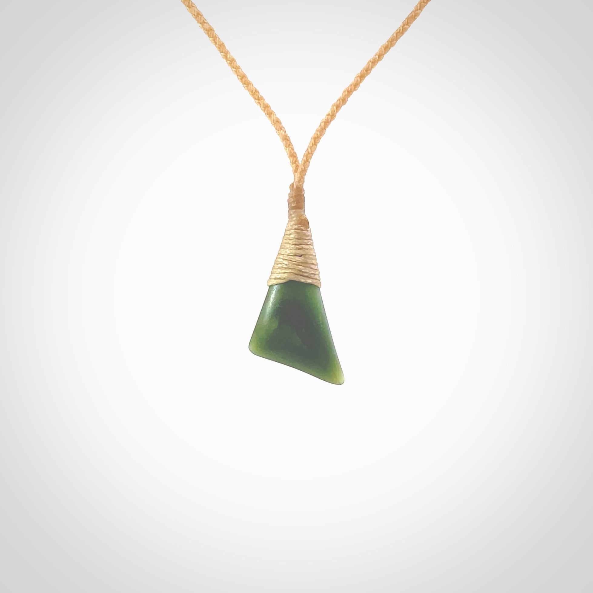 A lovely small sized New Zealand jade drop pendant. This piece is made from a dark, green jade and has a wonderful light green semi-translucent colour also. Carved by Ric Moor for NZ Pacific and delivered worldwide. Delivered with adjustable beige cord.