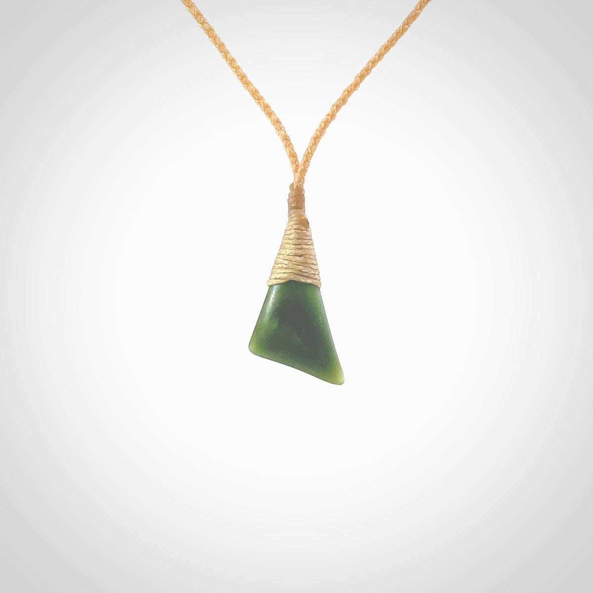 A lovely small sized New Zealand jade drop pendant. This piece is made from a dark, green jade and has a wonderful light green semi-translucent colour also. Carved by Ric Moor for NZ Pacific and delivered worldwide. Delivered with adjustable beige cord.