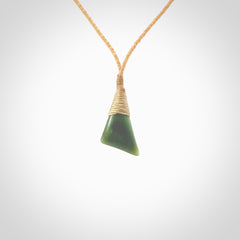 A lovely small sized New Zealand jade drop pendant. This piece is made from a dark, green jade and has a wonderful light green semi-translucent colour also. Carved by Ric Moor for NZ Pacific and delivered worldwide. Delivered with adjustable beige cord.