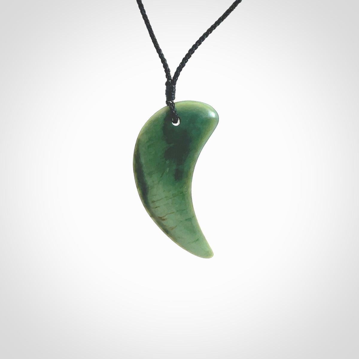 This is a lovely New Zealand Jade, pounamu drop pendant. Hand carved for us by Ric Moor. It is bound with an adjustable black cord which is length adjustable. Free worldwide shipping. The light reveals the internal structure and colour of the stone beautifully.