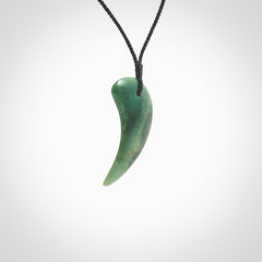 This is a lovely New Zealand Jade, pounamu drop pendant. Hand carved for us by Ric Moor. It is bound with an adjustable black cord which is length adjustable. Free worldwide shipping. The light reveals the internal structure and colour of the stone beautifully.