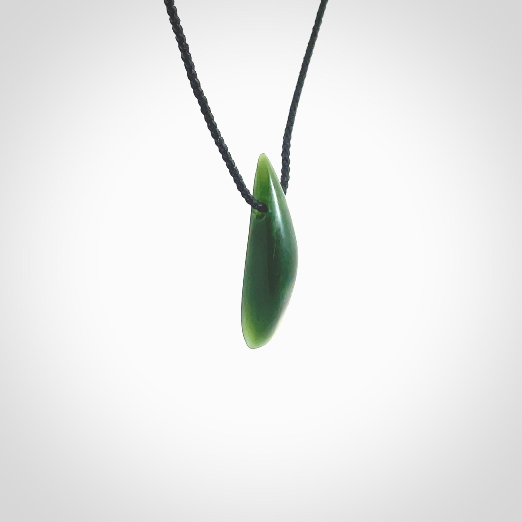 A lovely small sized New Zealand Marsden jade drop pendant. This piece is made from a deep green jade with orange specks and is a wonderful colour. Carved by Ric Moor for NZ Pacific and delivered worldwide. Provided with an adjustable black cord.