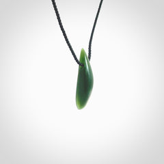 A lovely small sized New Zealand Marsden jade drop pendant. This piece is made from a deep green jade with orange specks and is a wonderful colour. Carved by Ric Moor for NZ Pacific and delivered worldwide. Provided with an adjustable black cord.