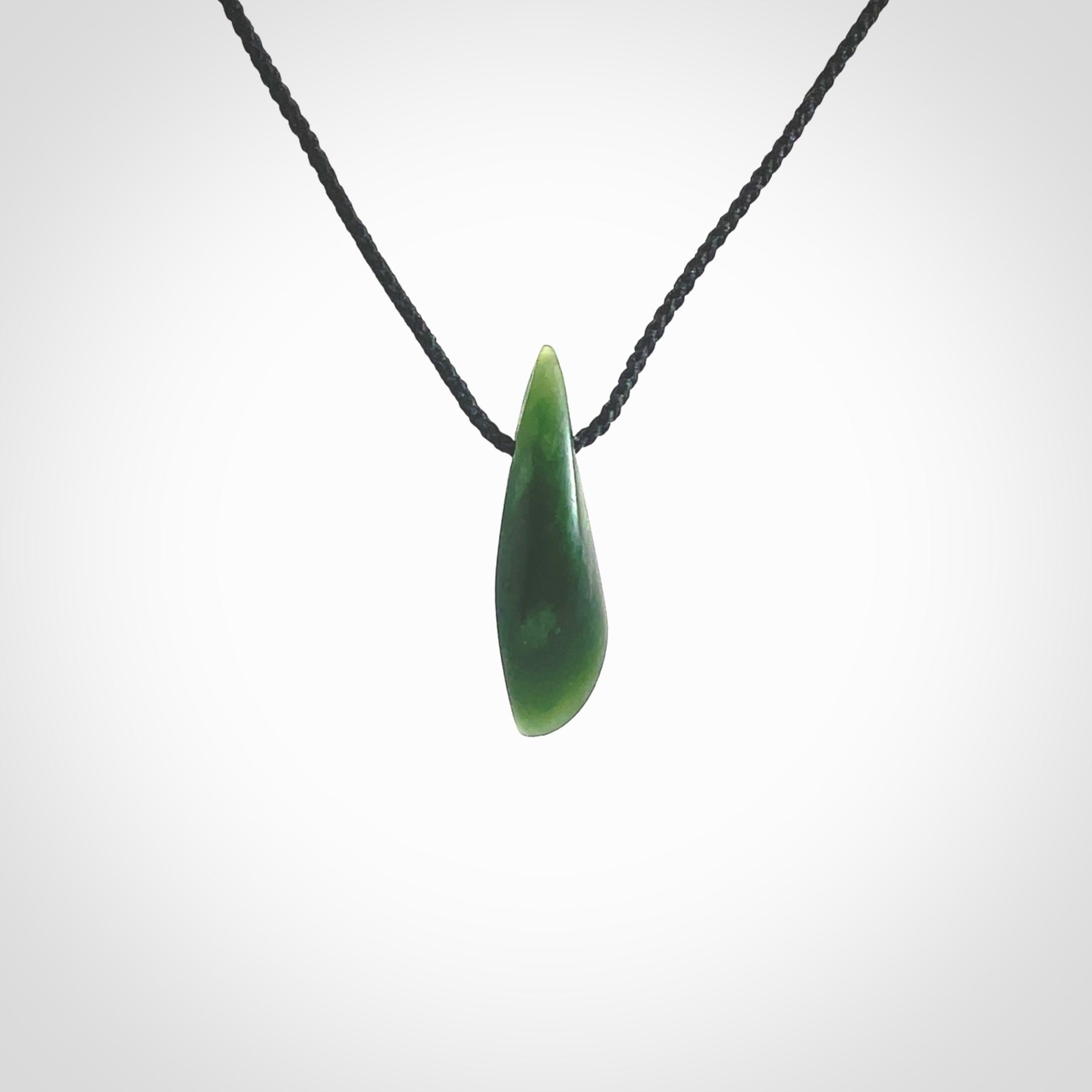 A lovely small sized New Zealand Marsden jade drop pendant. This piece is made from a deep green jade with orange specks and is a wonderful colour. Carved by Ric Moor for NZ Pacific and delivered worldwide. Provided with an adjustable black cord.