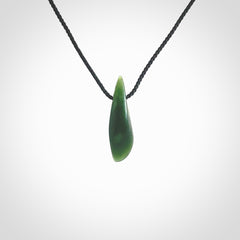 A lovely small sized New Zealand Marsden jade drop pendant. This piece is made from a deep green jade with orange specks and is a wonderful colour. Carved by Ric Moor for NZ Pacific and delivered worldwide. Provided with an adjustable black cord.