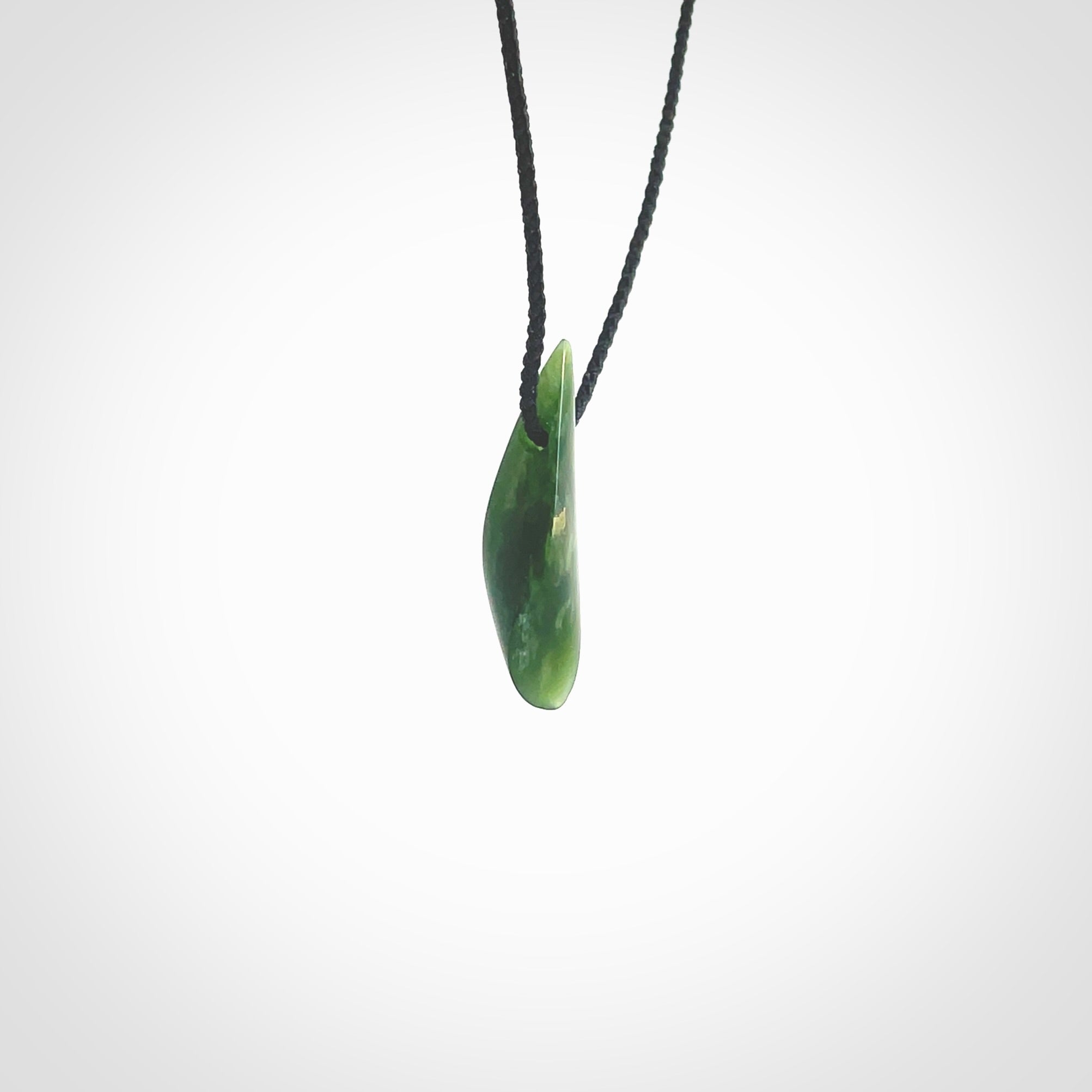 A lovely small sized New Zealand Marsden jade drop pendant. This piece is made from a deep green jade with orange specks and is a wonderful colour. Carved by Ric Moor for NZ Pacific and delivered worldwide. Provided with an adjustable black cord.