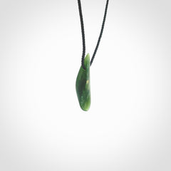 A lovely small sized New Zealand Marsden jade drop pendant. This piece is made from a deep green jade with orange specks and is a wonderful colour. Carved by Ric Moor for NZ Pacific and delivered worldwide. Provided with an adjustable black cord.