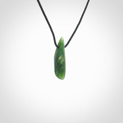 A lovely small sized New Zealand Marsden jade drop pendant. This piece is made from a deep green jade with orange specks and is a wonderful colour. Carved by Ric Moor for NZ Pacific and delivered worldwide. Provided with an adjustable black cord.