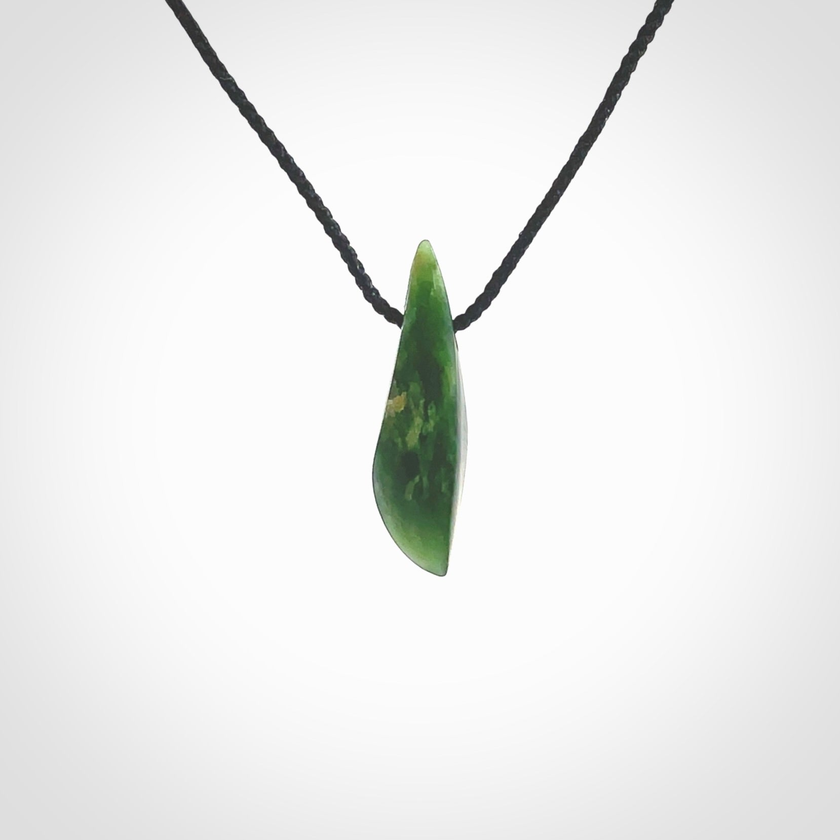 A lovely small sized New Zealand Marsden jade drop pendant. This piece is made from a deep green jade with orange specks and is a wonderful colour. Carved by Ric Moor for NZ Pacific and delivered worldwide. Provided with an adjustable black cord.