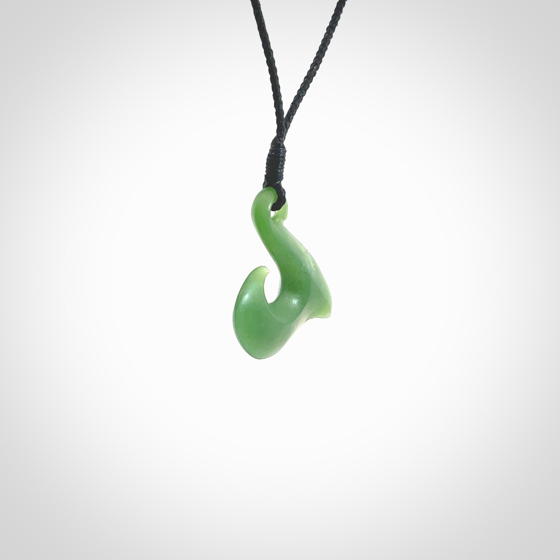 New Zealand jade hei-mate pendant. Hand carved in bright green jade by Ric Moor. The pendant is suspended from a black plaited cord and is finished in a satin matte polish.