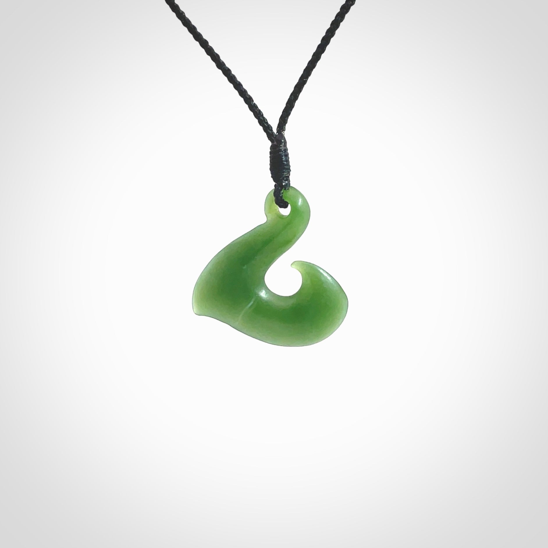 New Zealand jade hei-mate pendant. Hand carved in bright green jade by Ric Moor. The pendant is suspended from a black plaited cord and is finished in a satin matte polish.