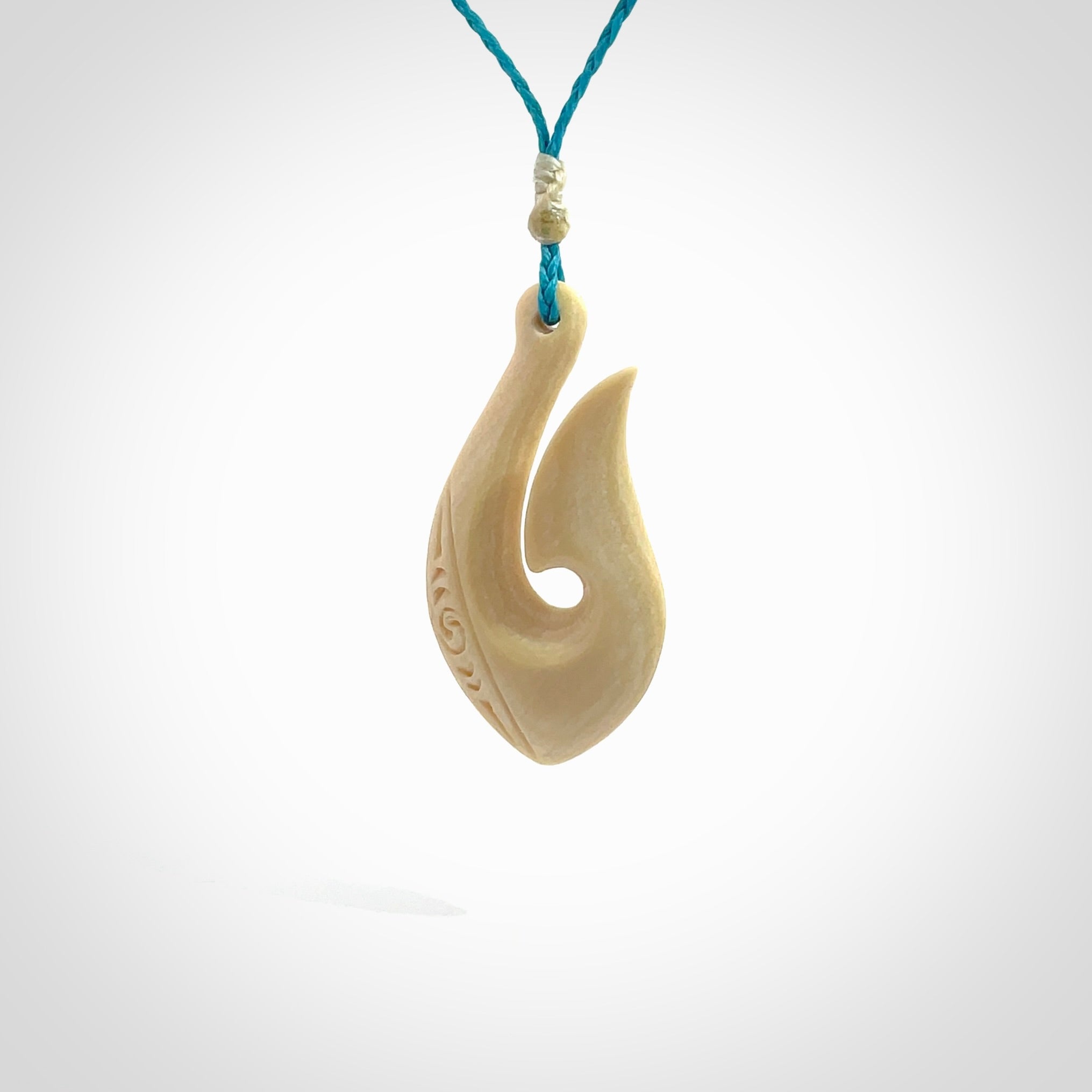 Hand carved ancient woolly mammoth tusk hook necklace with adjustable cord. Mammoth Tusk stabilised with blue resin pendant. Unique medium sized hook necklaces hand made from woolly mammoth tusk. Real ancient mammoth tusk delivered in a woven kete pouch.