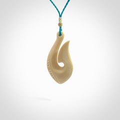 Hand carved ancient woolly mammoth tusk hook necklace with adjustable cord. Mammoth Tusk stabilised with blue resin pendant. Unique medium sized hook necklaces hand made from woolly mammoth tusk. Real ancient mammoth tusk delivered in a woven kete pouch.