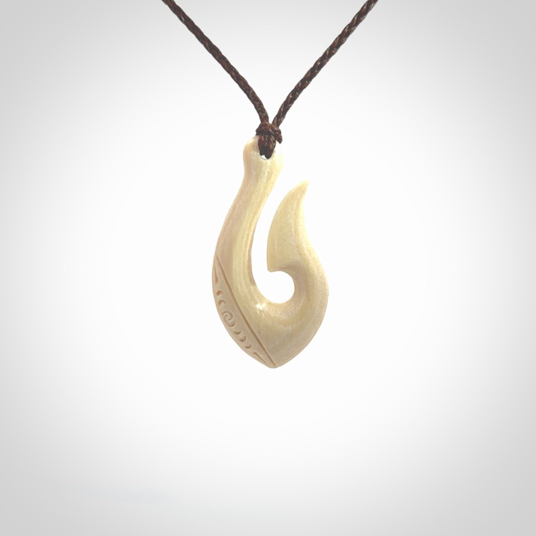 Hand carved ancient woolly mammoth tusk hook necklace with adjustable cord. Mammoth Tusk stabilised with blue resin pendant. Unique medium sized hook necklaces hand made from woolly mammoth tusk. Real ancient mammoth tusk delivered in a woven kete pouch.