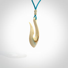 Hand carved ancient woolly mammoth tusk hook necklace with adjustable cord. Mammoth Tusk stabilised with blue resin pendant. Unique medium sized hook necklaces hand made from woolly mammoth tusk. Real ancient mammoth tusk delivered in a woven kete pouch.