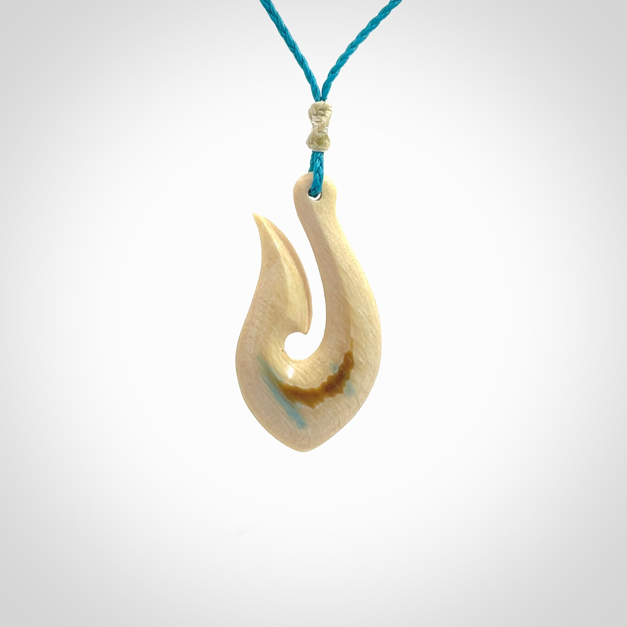 Hand carved ancient woolly mammoth tusk hook necklace with adjustable cord. Mammoth Tusk stabilised with blue resin pendant. Unique medium sized hook necklaces hand made from woolly mammoth tusk. Real ancient mammoth tusk delivered in a woven kete pouch.