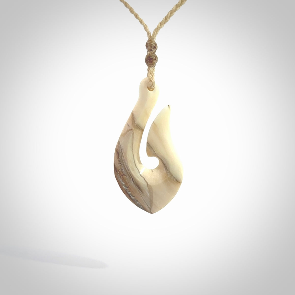 Hand carved ancient woolly mammoth tusk hook necklace with adjustable cord. Mammoth Tusk stabilised with blue resin pendant. Unique medium sized hook necklaces hand made from woolly mammoth tusk. Real ancient mammoth tusk delivered in a woven kete pouch.