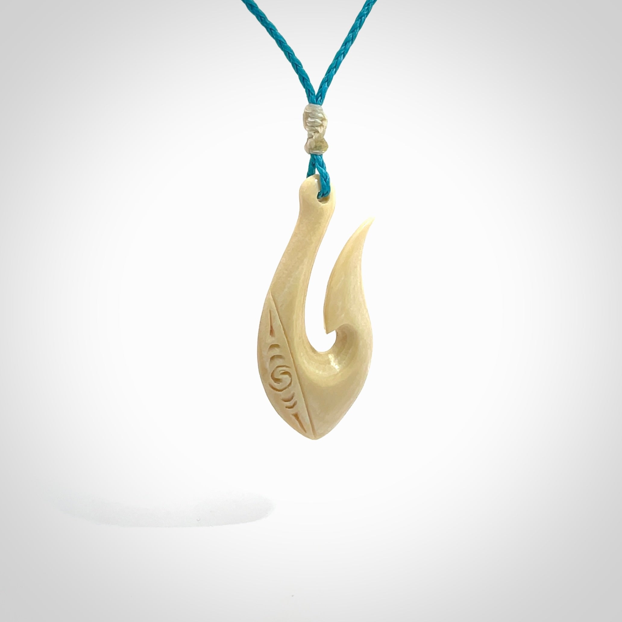 Hand carved ancient woolly mammoth tusk hook necklace with adjustable cord. Mammoth Tusk stabilised with blue resin pendant. Unique medium sized hook necklaces hand made from woolly mammoth tusk. Real ancient mammoth tusk delivered in a woven kete pouch.