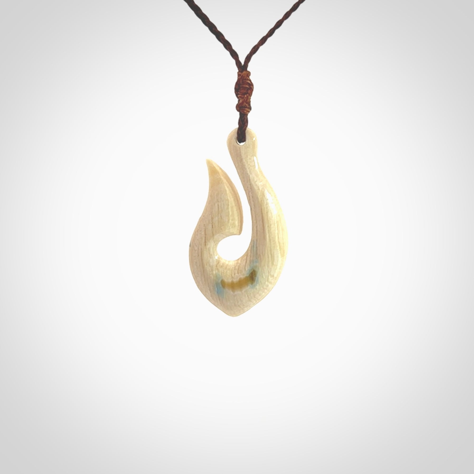 Hand carved ancient woolly mammoth tusk hook necklace with adjustable cord. Mammoth Tusk stabilised with blue resin pendant. Unique medium sized hook necklaces hand made from woolly mammoth tusk. Real ancient mammoth tusk delivered in a woven kete pouch.