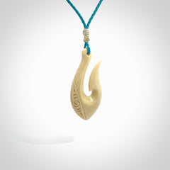 Hand carved ancient woolly mammoth tusk hook necklace with adjustable cord. Mammoth Tusk stabilised with blue resin pendant. Unique medium sized hook necklaces hand made from woolly mammoth tusk. Real ancient mammoth tusk delivered in a woven kete pouch.