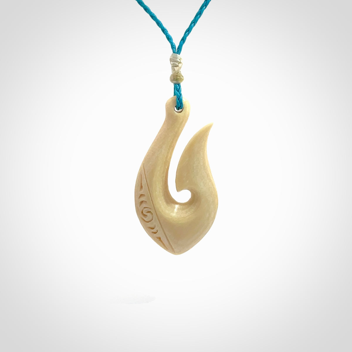 Hand carved ancient woolly mammoth tusk hook necklace with adjustable cord. Mammoth Tusk stabilised with blue resin pendant. Unique medium sized hook necklaces hand made from woolly mammoth tusk. Real ancient mammoth tusk delivered in a woven kete pouch.