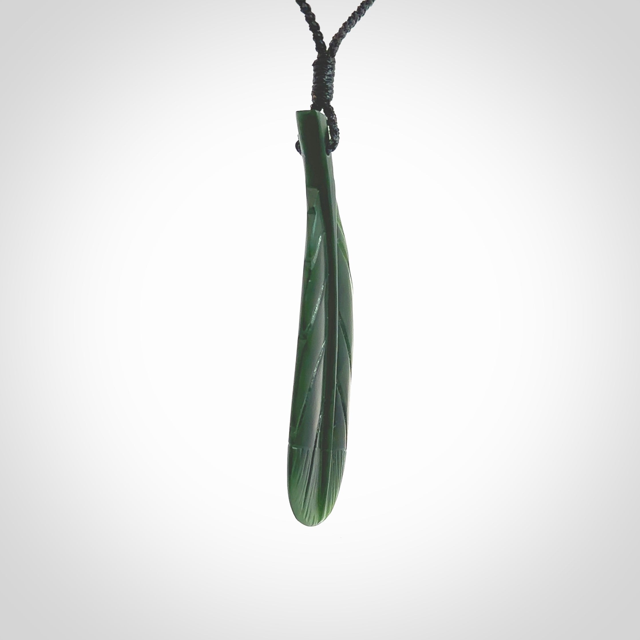 Hand carved New Zealand Jade huia feather pendant. Made by Ana Krakosky for NZ Pacific in New Zealand Pounamu, jade. A beautiful dark green jade huia feather drop necklace with black adjustable cord.