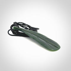 Hand carved New Zealand Jade huia feather pendant. Made by Ana Krakosky for NZ Pacific in New Zealand Pounamu, jade. A beautiful dark green jade huia feather drop necklace with black adjustable cord.