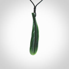 Hand carved New Zealand Jade huia feather pendant. Made by Ana Krakosky for NZ Pacific in New Zealand Pounamu, jade. A beautiful dark green jade huia feather drop necklace with black adjustable cord.