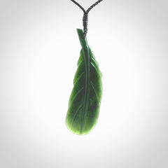 Hand carved New Zealand Jade huia feather pendant. Made by Ana Krakosky for NZ Pacific in New Zealand Pounamu, jade. A beautiful dark green jade huia feather drop necklace with black adjustable cord.