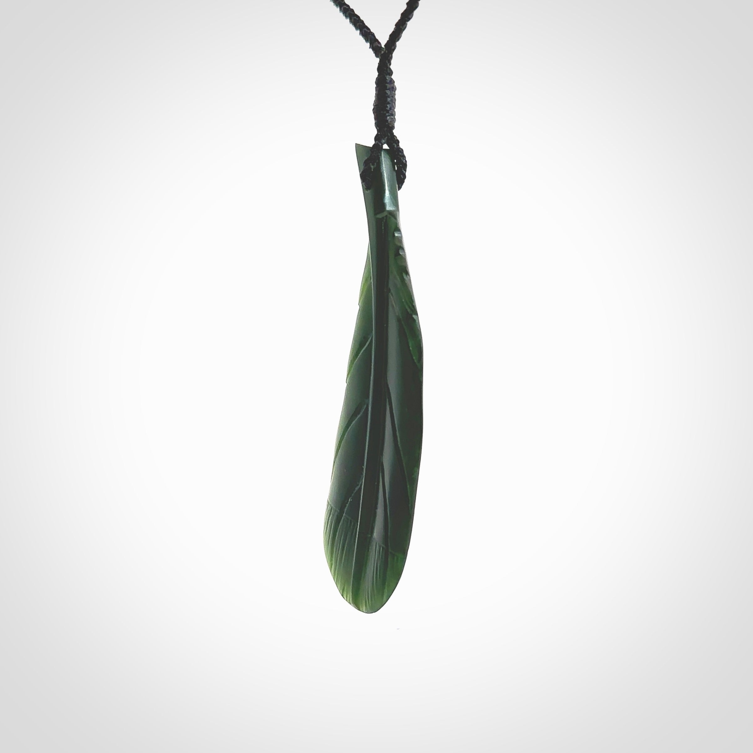 Hand carved New Zealand Jade huia feather pendant. Made by Ana Krakosky for NZ Pacific in New Zealand Pounamu, jade. A beautiful dark green jade huia feather drop necklace with black adjustable cord.