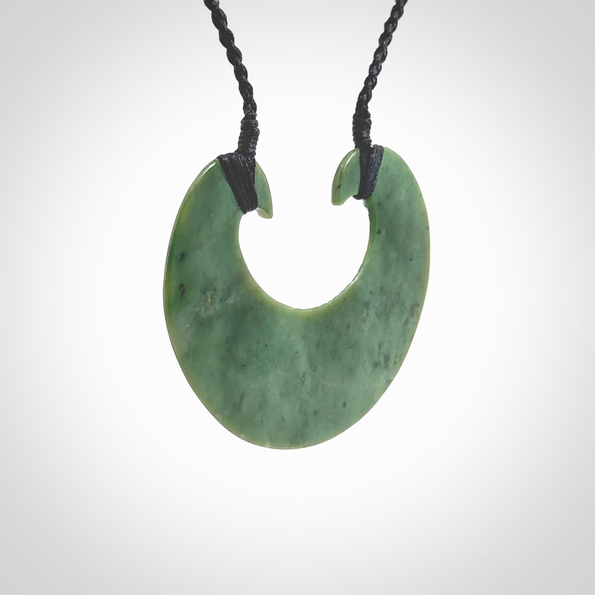 Hand carved New Zealand Jade chest plate pendant. Made by Ana Krakosky for NZ Pacific in New Zealand Pounamu, jade. A beautiful light green jade chest plate drop necklace with black adjustable cord.