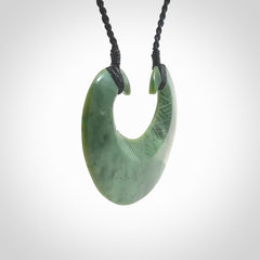 Hand carved New Zealand Jade chest plate pendant. Made by Ana Krakosky for NZ Pacific in New Zealand Pounamu, jade. A beautiful light green jade chest plate drop necklace with black adjustable cord.