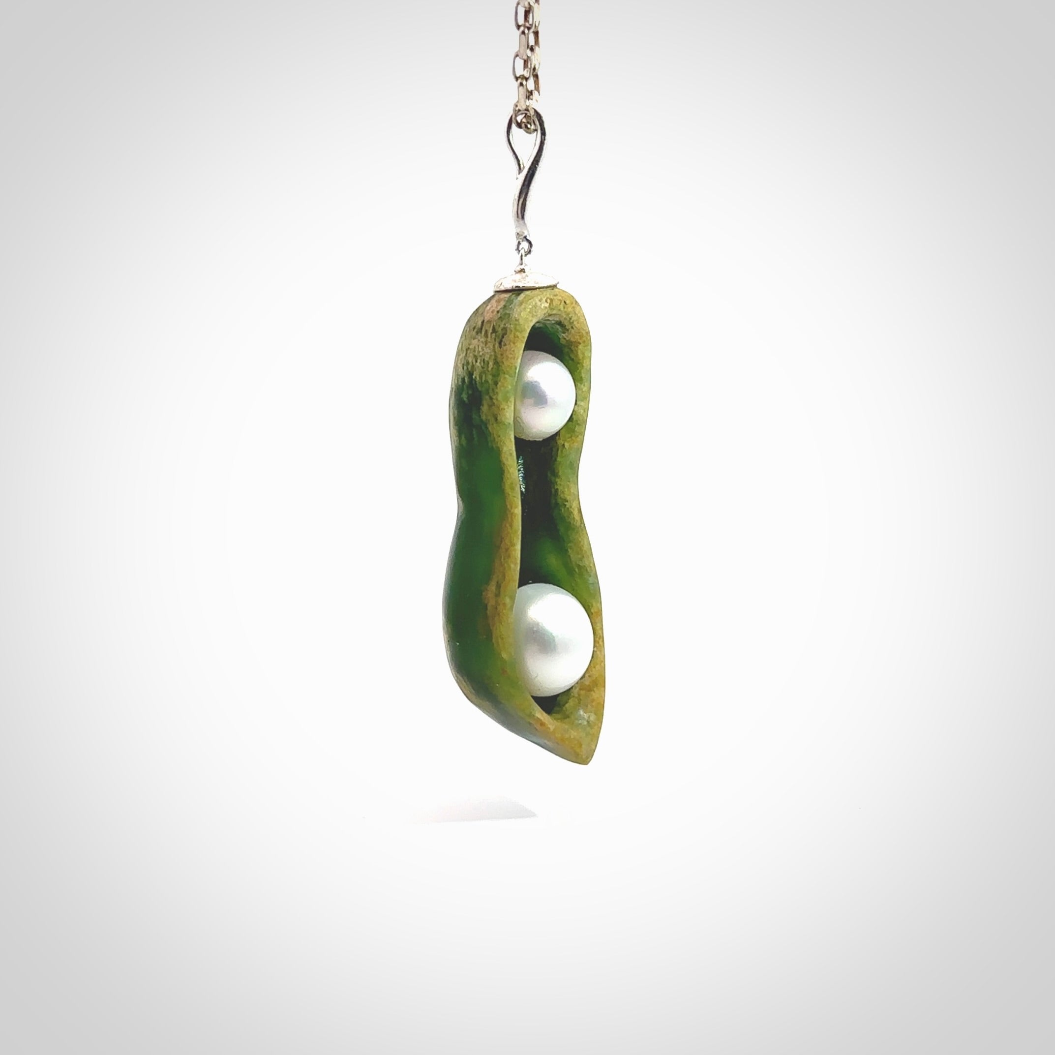 Hand carved New Zealand Marsden Jade two peas in a pod drop pendant with two pearl inlays. Made by Ana Krakosky for NZ Pacific in New Zealand Pounamu, flower jade with real pearls. A beautiful dark green and orange jade representing two peas in a pod. A drop with pearl inserts necklace with long sterling silver chain. One only, provided in a wooden gift box and delivered with express courier.