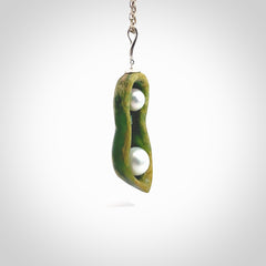 Hand carved New Zealand Marsden Jade two peas in a pod drop pendant with two pearl inlays. Made by Ana Krakosky for NZ Pacific in New Zealand Pounamu, flower jade with real pearls. A beautiful dark green and orange jade representing two peas in a pod. A drop with pearl inserts necklace with long sterling silver chain. One only, provided in a wooden gift box and delivered with express courier.