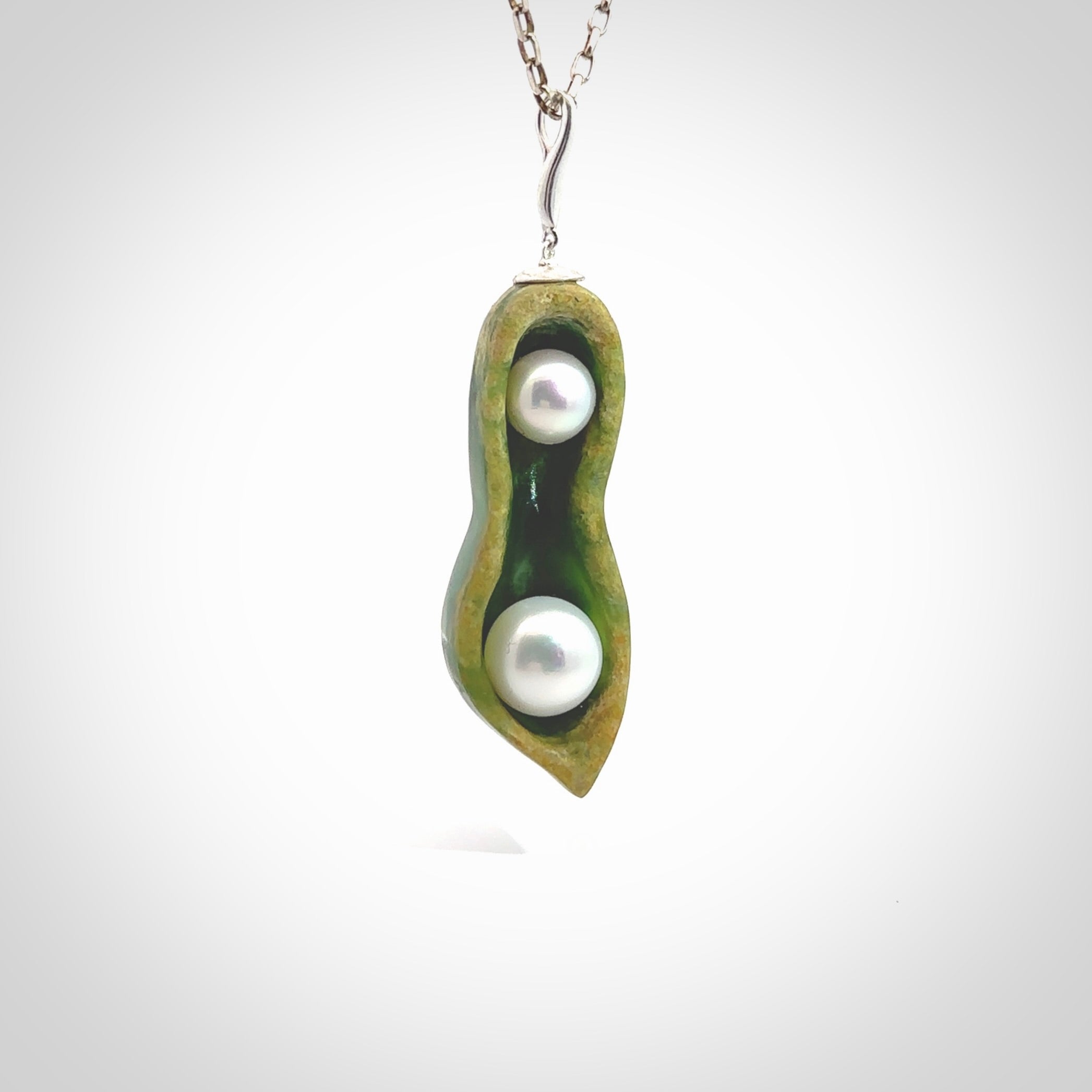 Hand carved New Zealand Marsden Jade two peas in a pod drop pendant with two pearl inlays. Made by Ana Krakosky for NZ Pacific in New Zealand Pounamu, flower jade with real pearls. A beautiful dark green and orange jade representing two peas in a pod. A drop with pearl inserts necklace with long sterling silver chain. One only, provided in a wooden gift box and delivered with express courier.