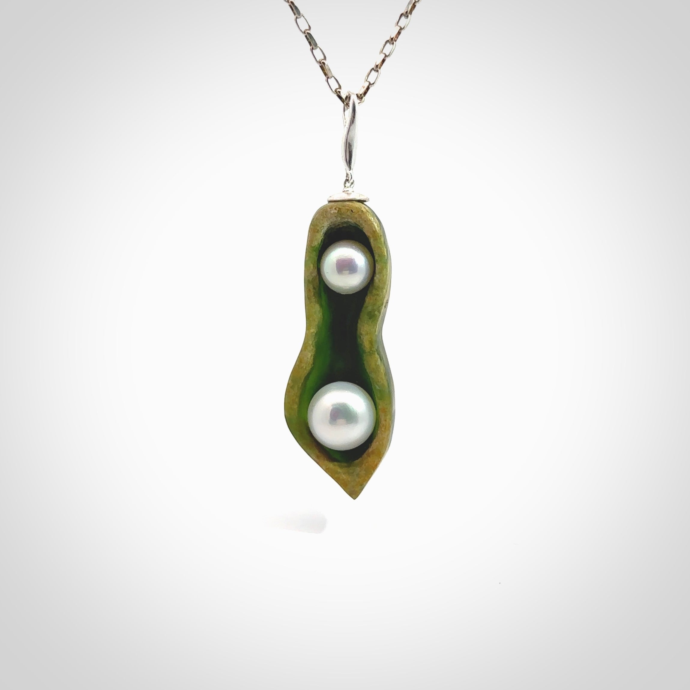 Hand carved New Zealand Marsden Jade two peas in a pod drop pendant with two pearl inlays. Made by Ana Krakosky for NZ Pacific in New Zealand Pounamu, flower jade with real pearls. A beautiful dark green and orange jade representing two peas in a pod. A drop with pearl inserts necklace with long sterling silver chain. One only, provided in a wooden gift box and delivered with express courier.