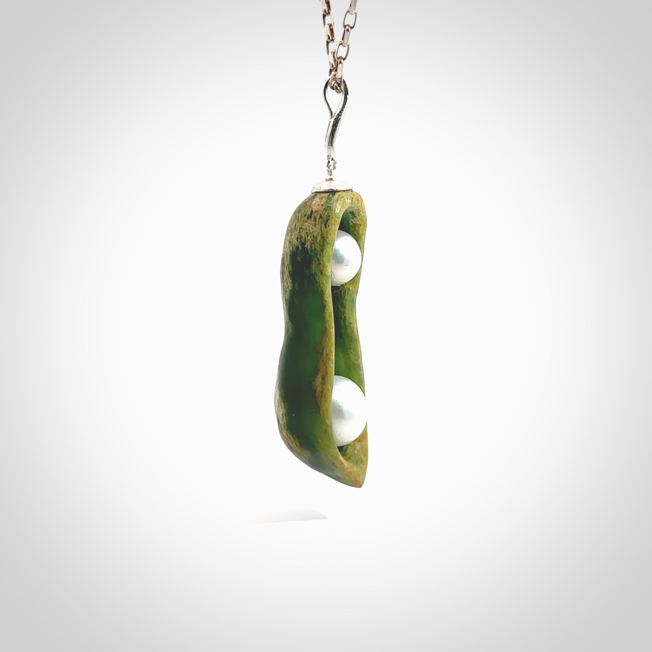 Hand carved New Zealand Marsden Jade two peas in a pod drop pendant with two pearl inlays. Made by Ana Krakosky for NZ Pacific in New Zealand Pounamu, flower jade with real pearls. A beautiful dark green and orange jade representing two peas in a pod. A drop with pearl inserts necklace with long sterling silver chain. One only, provided in a wooden gift box and delivered with express courier.