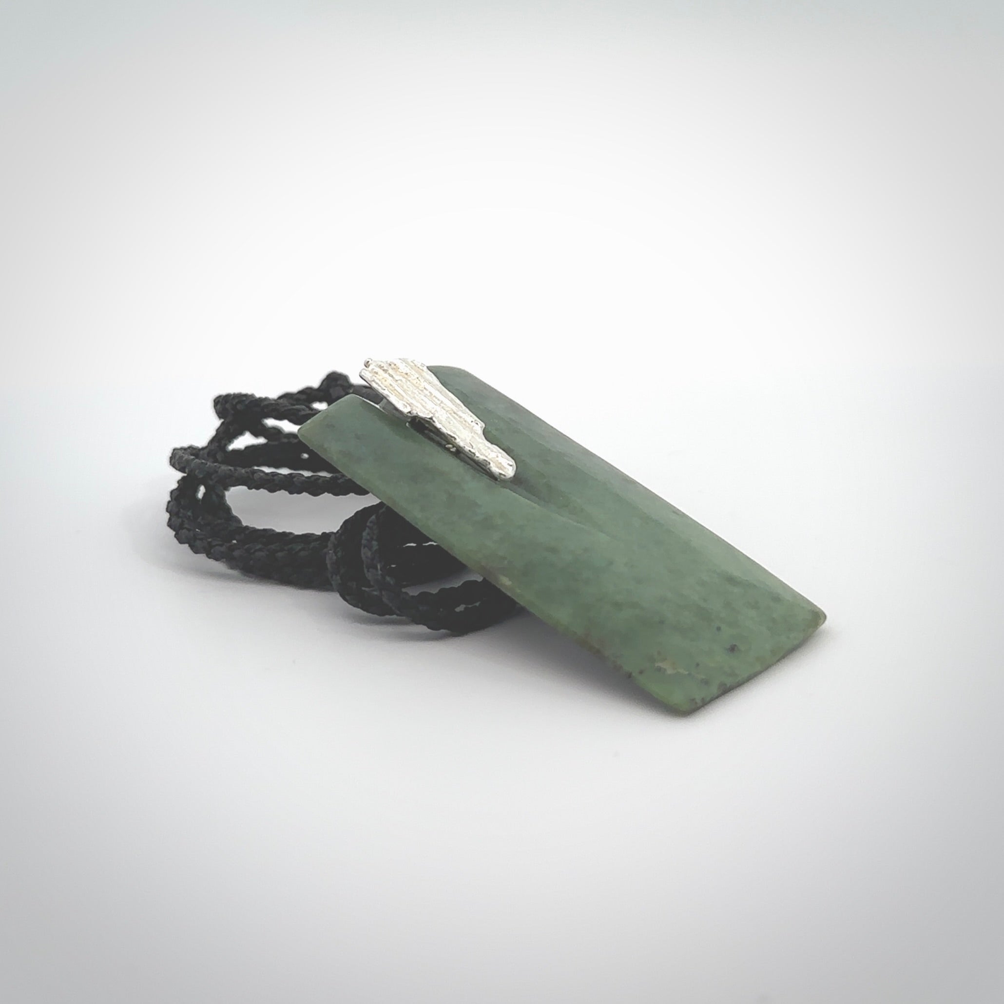 A charismatic pendant carved from New Zealand Pounamu. This is a medium sized, rectangle drop with a silver cast shard inlay on the front. Hand made by wonderful artist and carver; Ana Krakosky.