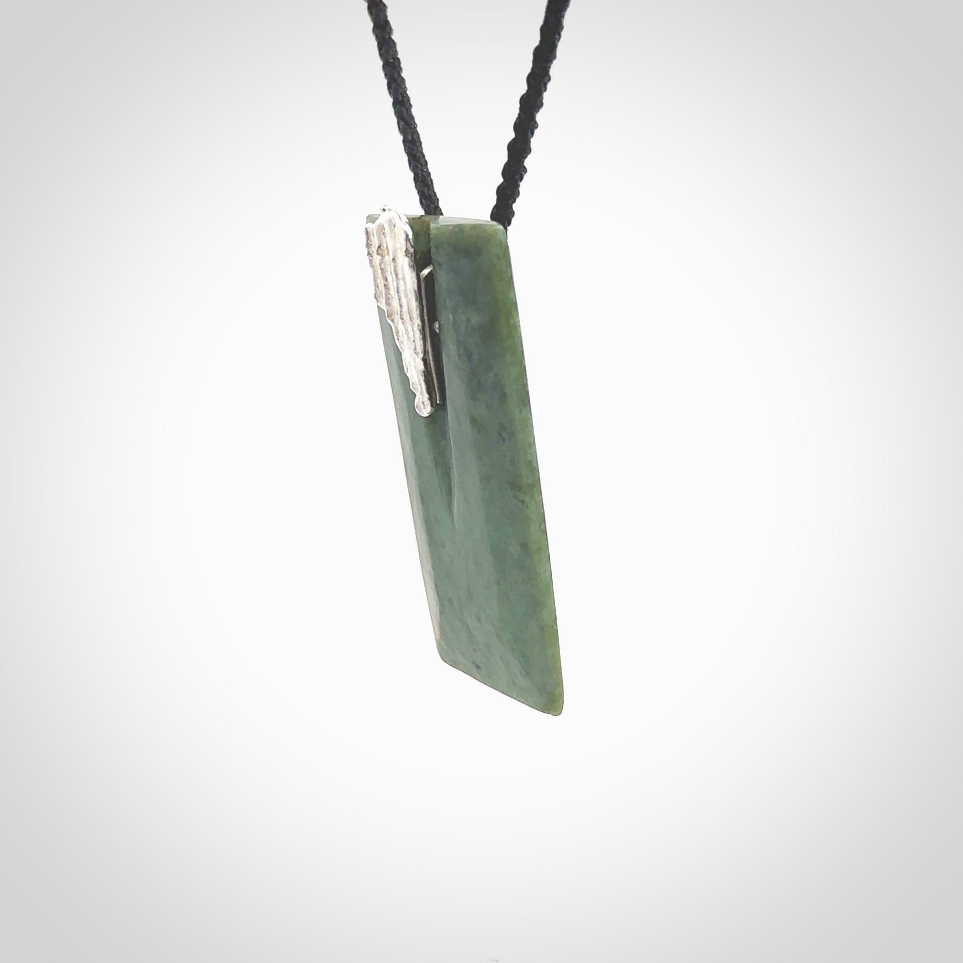 A charismatic pendant carved from New Zealand Pounamu. This is a medium sized, rectangle drop with a silver cast shard inlay on the front. Hand made by wonderful artist and carver; Ana Krakosky.