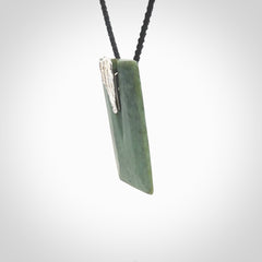 A charismatic pendant carved from New Zealand Pounamu. This is a medium sized, rectangle drop with a silver cast shard inlay on the front. Hand made by wonderful artist and carver; Ana Krakosky.