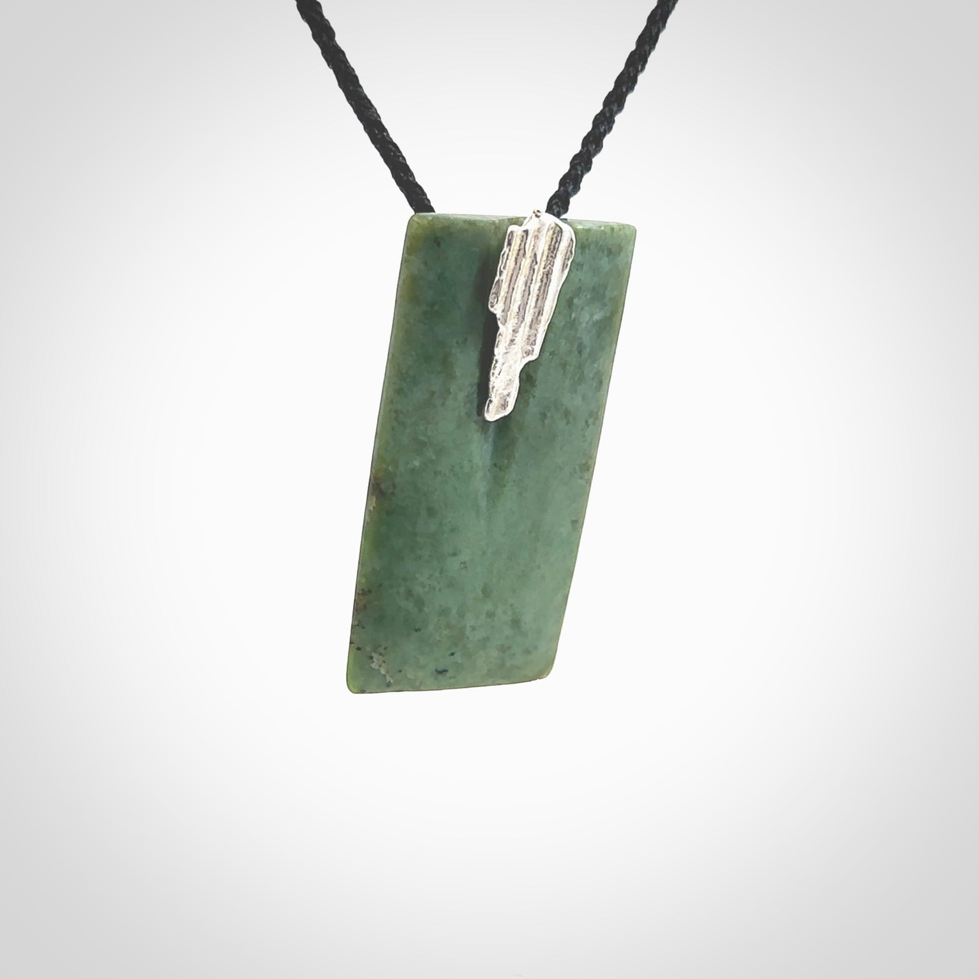 A charismatic pendant carved from New Zealand Pounamu. This is a medium sized, rectangle drop with a silver cast shard inlay on the front. Hand made by wonderful artist and carver; Ana Krakosky.