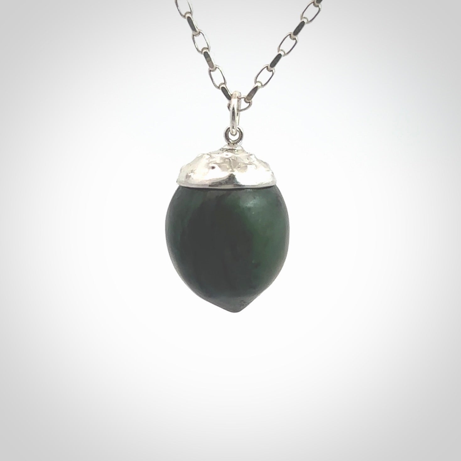 This picture shows a little jade acorn pendant with sterling silver chain. The cap is sterling silver and is embossed with some decorative markings which give the silver cap some detail and character. Hand made by Ana Krakosky.