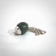 This picture shows a little jade acorn pendant with sterling silver chain. The cap is sterling silver and is embossed with some decorative markings which give the silver cap some detail and character. Hand made by Ana Krakosky.