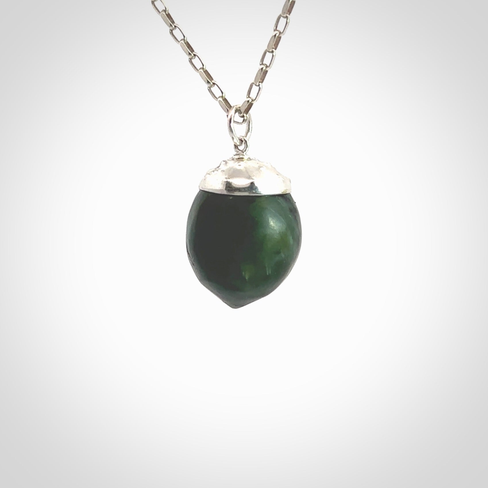 This picture shows a little jade acorn pendant with sterling silver chain. The cap is sterling silver and is embossed with some decorative markings which give the silver cap some detail and character. Hand made by Ana Krakosky.