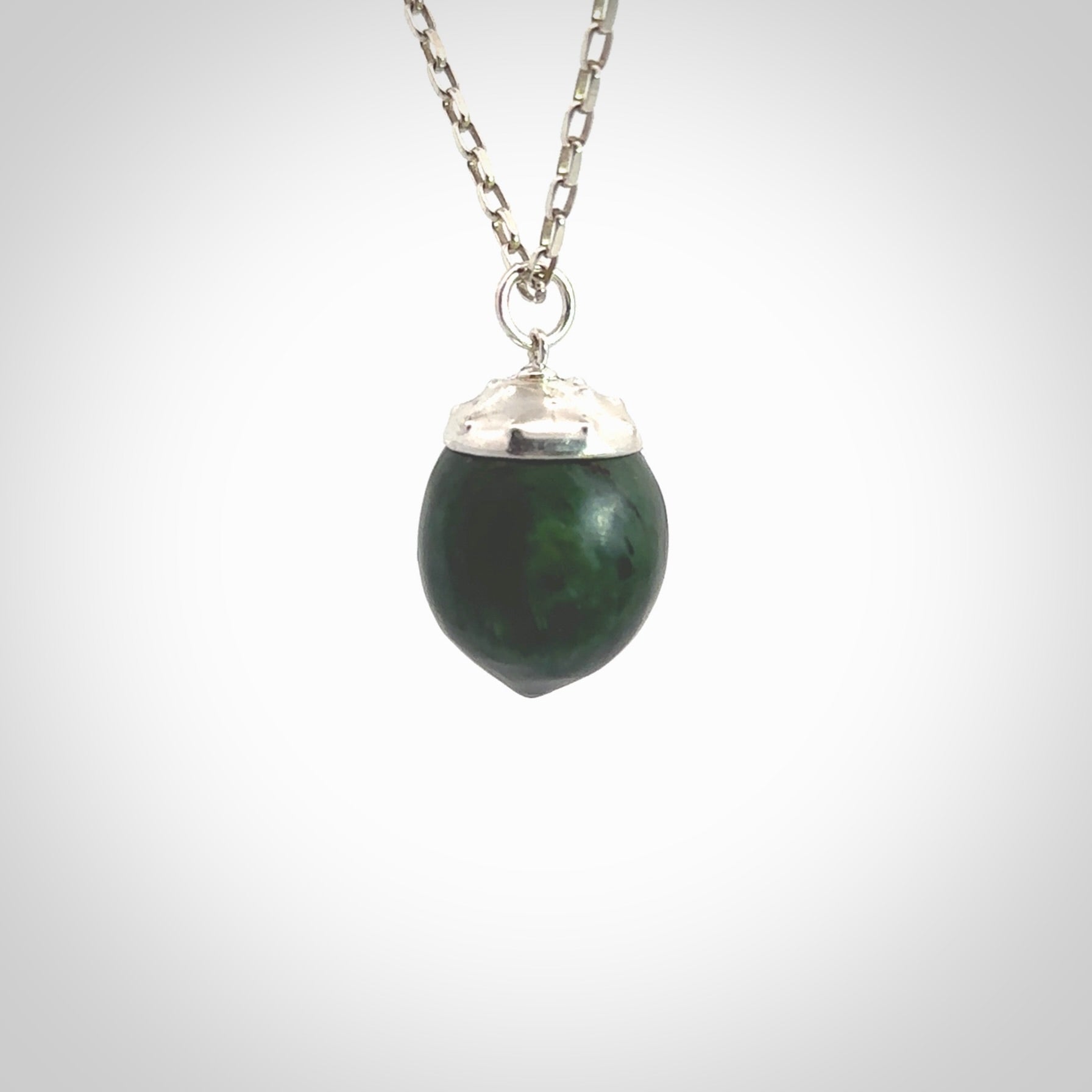 This picture shows a little jade acorn pendant with sterling silver chain. The cap is sterling silver and is embossed with some decorative markings which give the silver cap some detail and character. Hand made by Ana Krakosky.