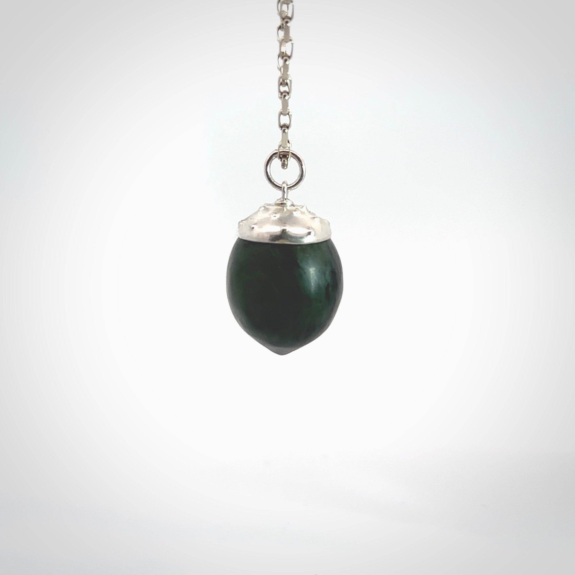 This picture shows a little jade acorn pendant with sterling silver chain. The cap is sterling silver and is embossed with some decorative markings which give the silver cap some detail and character. Hand made by Ana Krakosky.