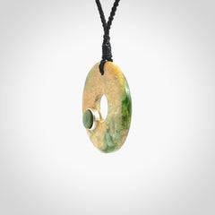 Hand carved New Zealand flower Jade disc drop pendant with smaller pounamu and silver insert. Made by Ana Krakosky for NZ Pacific in New Zealand Pounamu, jade. A beautiful orange and green jade disc necklace with black adjustable cord.