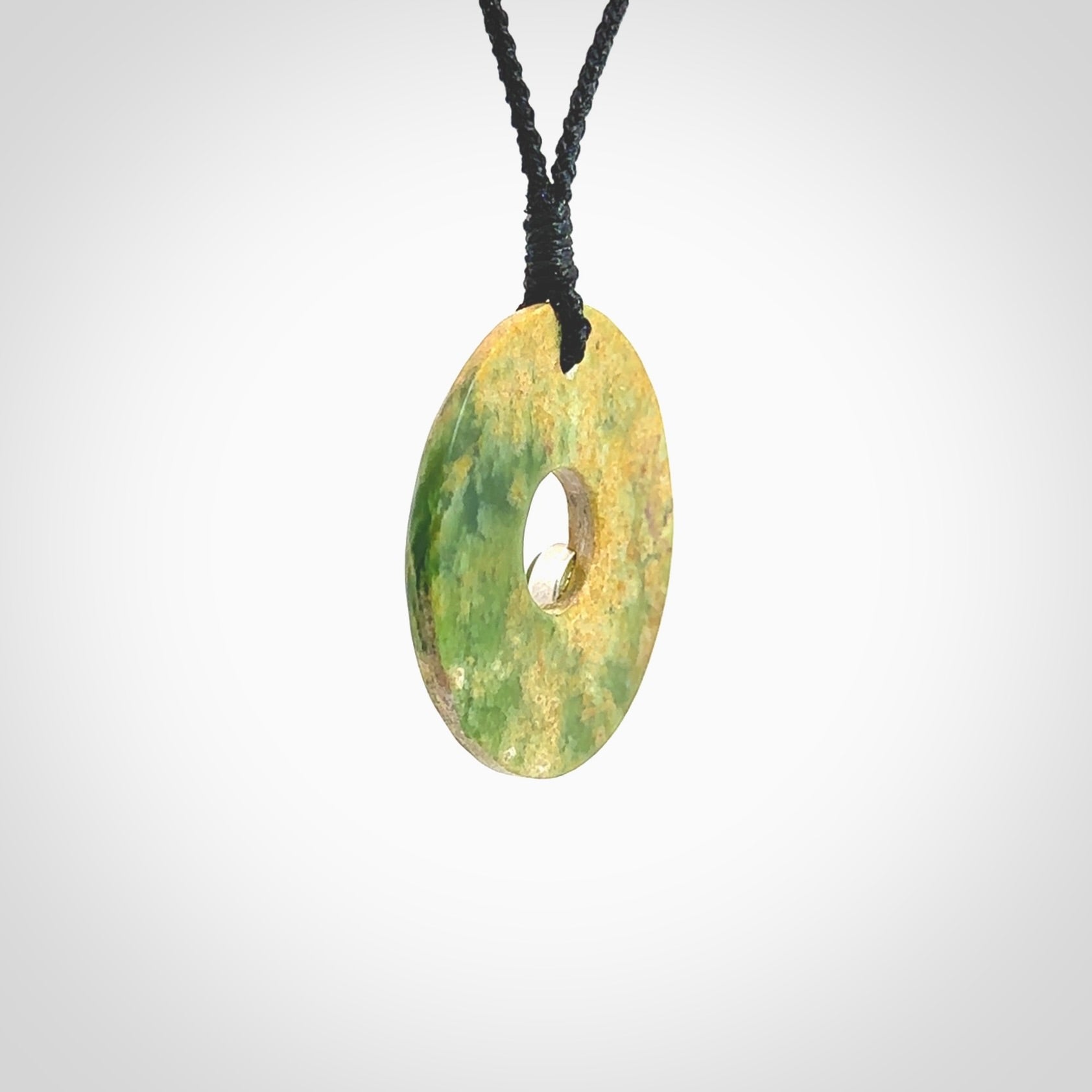 Hand carved New Zealand flower Jade disc drop pendant with smaller pounamu and silver insert. Made by Ana Krakosky for NZ Pacific in New Zealand Pounamu, jade. A beautiful orange and green jade disc necklace with black adjustable cord.