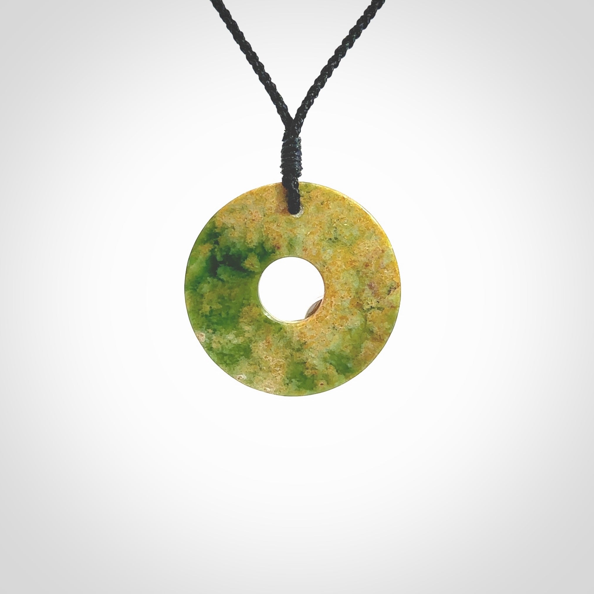 Hand carved New Zealand flower Jade disc drop pendant with smaller pounamu and silver insert. Made by Ana Krakosky for NZ Pacific in New Zealand Pounamu, jade. A beautiful orange and green jade disc necklace with black adjustable cord.