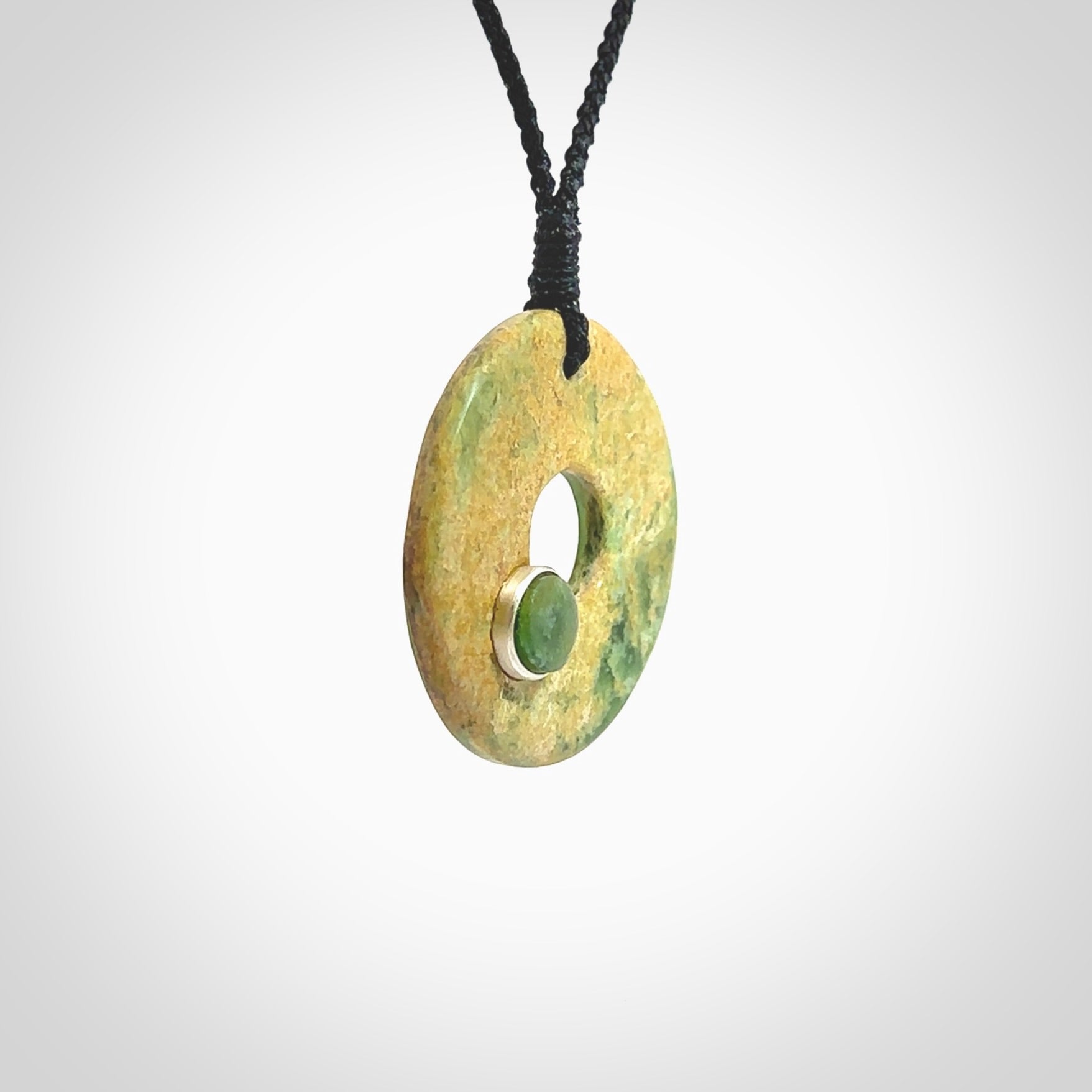 Hand carved New Zealand flower Jade disc drop pendant with smaller pounamu and silver insert. Made by Ana Krakosky for NZ Pacific in New Zealand Pounamu, jade. A beautiful orange and green jade disc necklace with black adjustable cord.